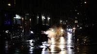 a person riding a bike on a wet street at night